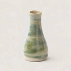 Ceramic vase with green and beige glaze on a light gray background