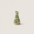 A small handmade ceramic bud vase with a green and beige marbled glaze, centered against a solid light beige background.