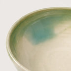 Close-up of a ceramic bowl with a gradient color from green to beige on a white background