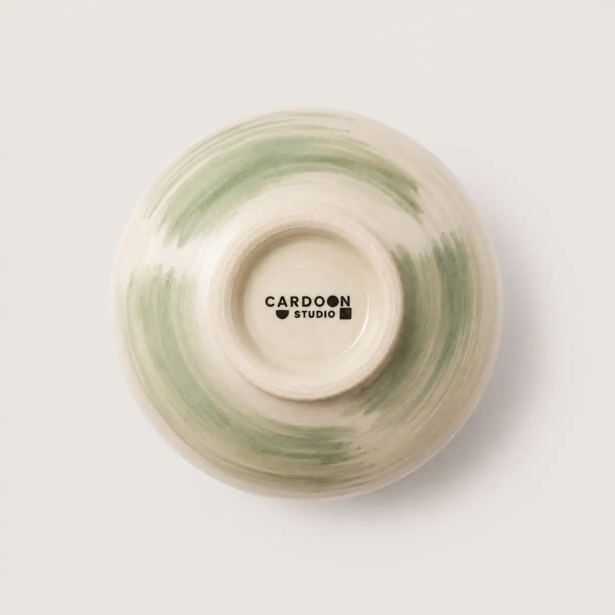 Ceramic bowl with green and beige swirl pattern on a white background, featuring 'Cardoon Studio' branding.