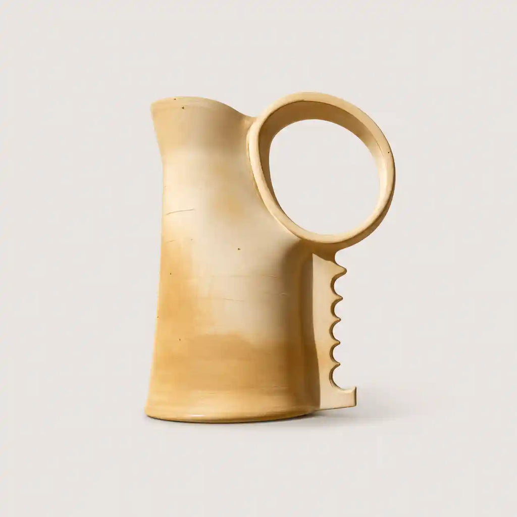 A light natural wood pitcher with a unique ring handle and a wavy cutout detail on the side, shown against a solid light gray background.