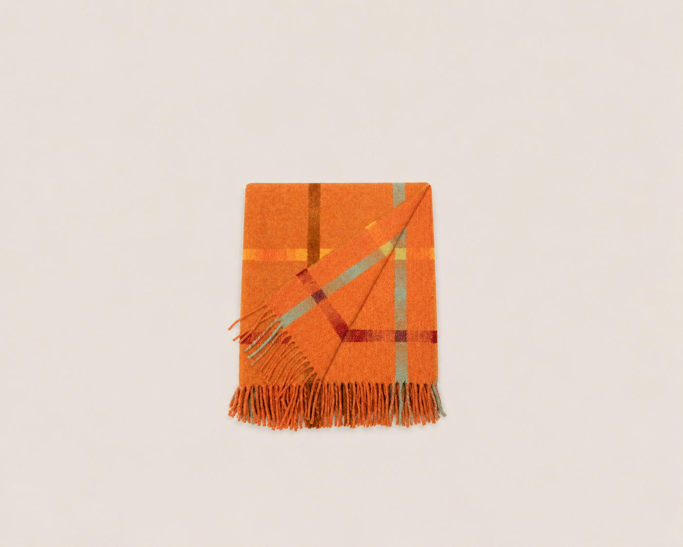 An orange plaid throw blanket with fringe, folded diagonally on a light beige background.