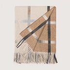 A folded woven wool throw blanket with fringe, featuring a classic check pattern in beige, brown, white, and dark gray on a light cream background.