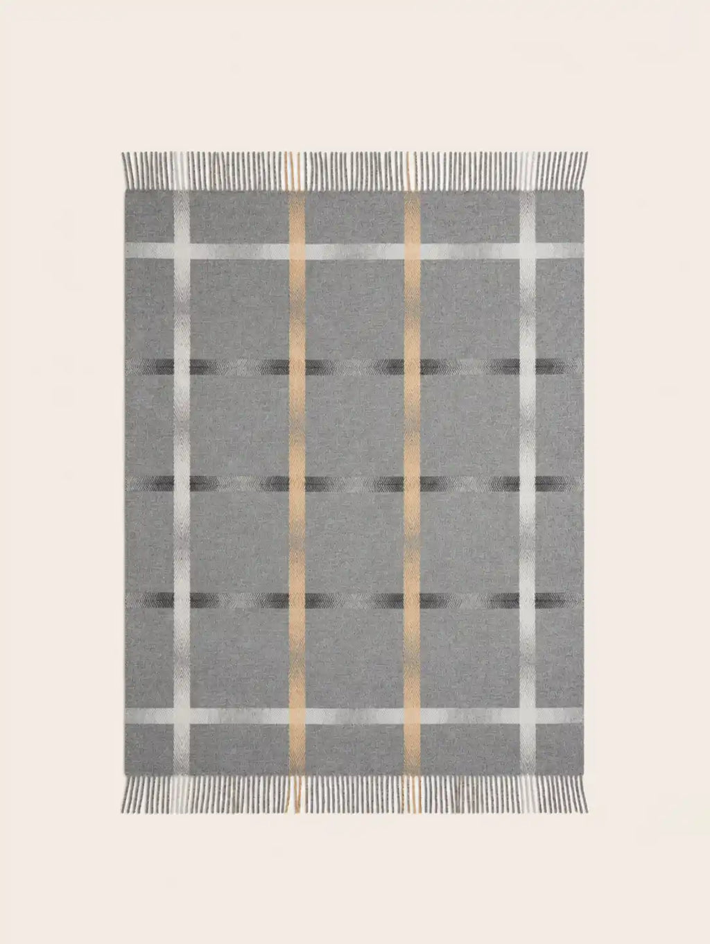 A rectangular merino wool gray woven throw blanket with a plaid pattern, featuring vertical metallic gold stripes, horizontal white stripes, and fringed edges on all sides, shown flat against a light beige background.