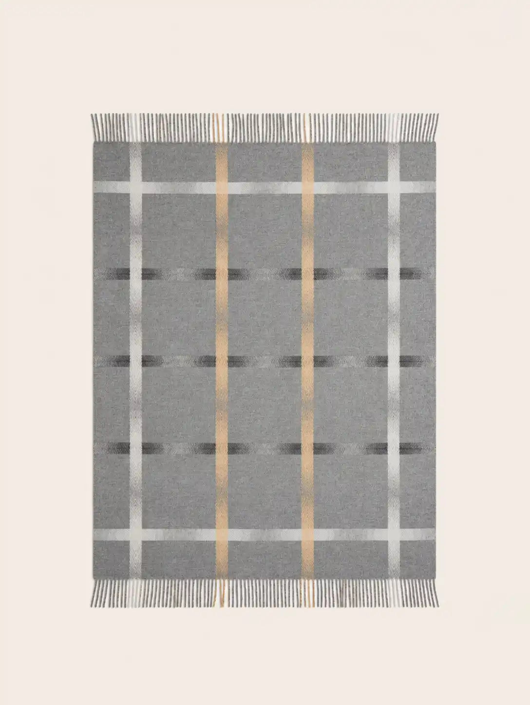 A rectangular merino wool gray woven throw blanket with a plaid pattern, featuring vertical metallic gold stripes, horizontal white stripes, and fringed edges on all sides, shown flat against a light beige background.