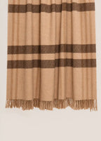 A close-up of a throw blanket with a beige and brown check pattern and fringed edges, shown against a light gray background.