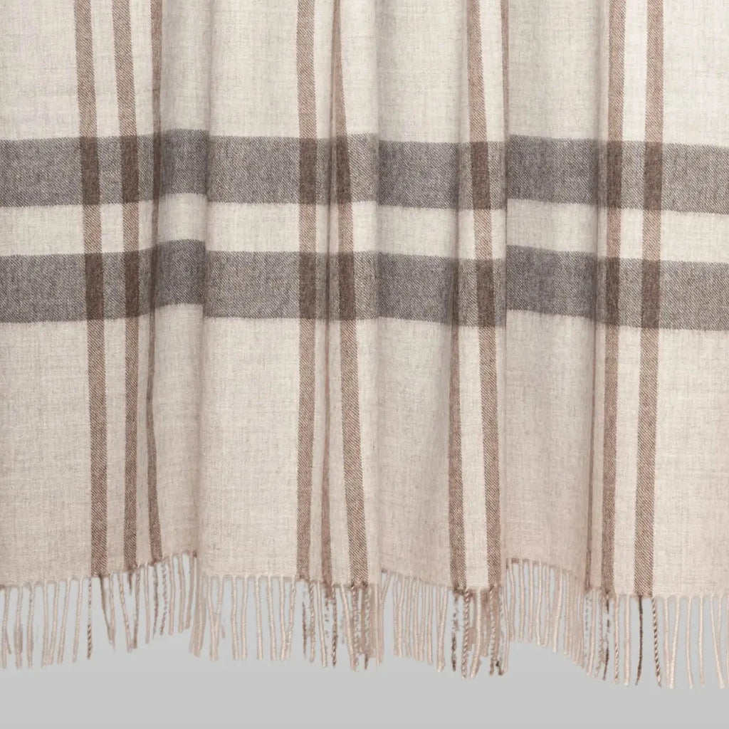 Plaid blanket with brown and gray stripes on a wooden stick against a white background