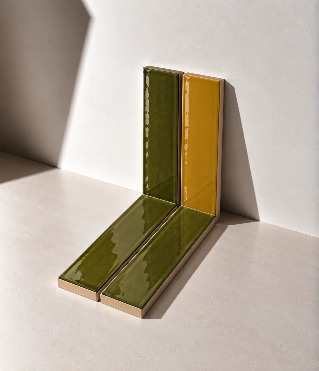 Glossy Moss Green and Amber Yellow handmade ceramic tiles arranged against a white wall in natural sunlight.