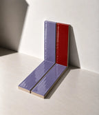 Glossy Scarlet Red and Lilac handmade ceramic tiles arranged against a white wall in natural sunlight.