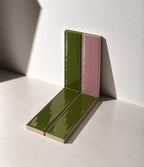 Glossy Olive Green and Dusty Pink handmade ceramic tiles arranged against a white wall in natural sunlight.