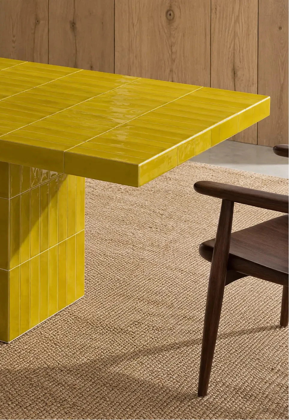 Glossy citron citron yellow rectangular ceramic tiles covering a dining table, paired with a dark wood chair and natural woven rug.