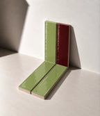 Glossy Sage Green and Burgundy Red handmade ceramic tiles arranged against a white wall in natural sunlight.