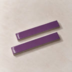 Two glossy purple rectangular ceramic tiles with silver metallic edges, displayed diagonally on a light beige textured background.