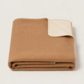 A folded tan wool throwblanket with a cream-colored reverse side, shown on a clean white background.