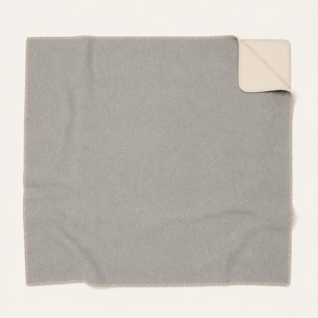 A square light gray throw blanket with a cream-colored underside, shown flat on a white background with one corner folded over.