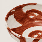 Ceramic snack bowl with brown abstract patterns on a light background