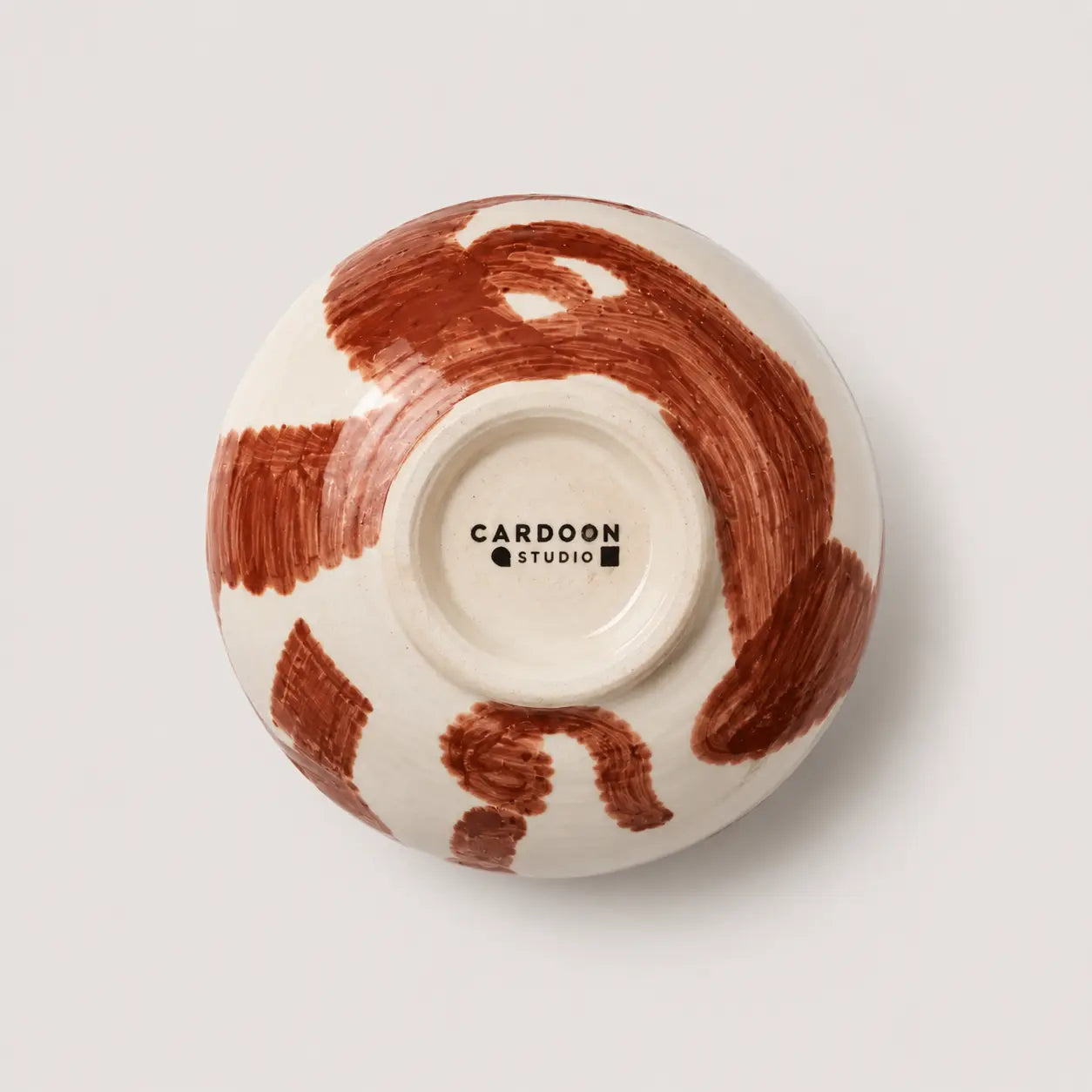 Ceramic bowl with brown abstract design on a white background, featuring the Cardoon Studio logo.