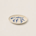 Beige plate with blue fish illustrations on a white background