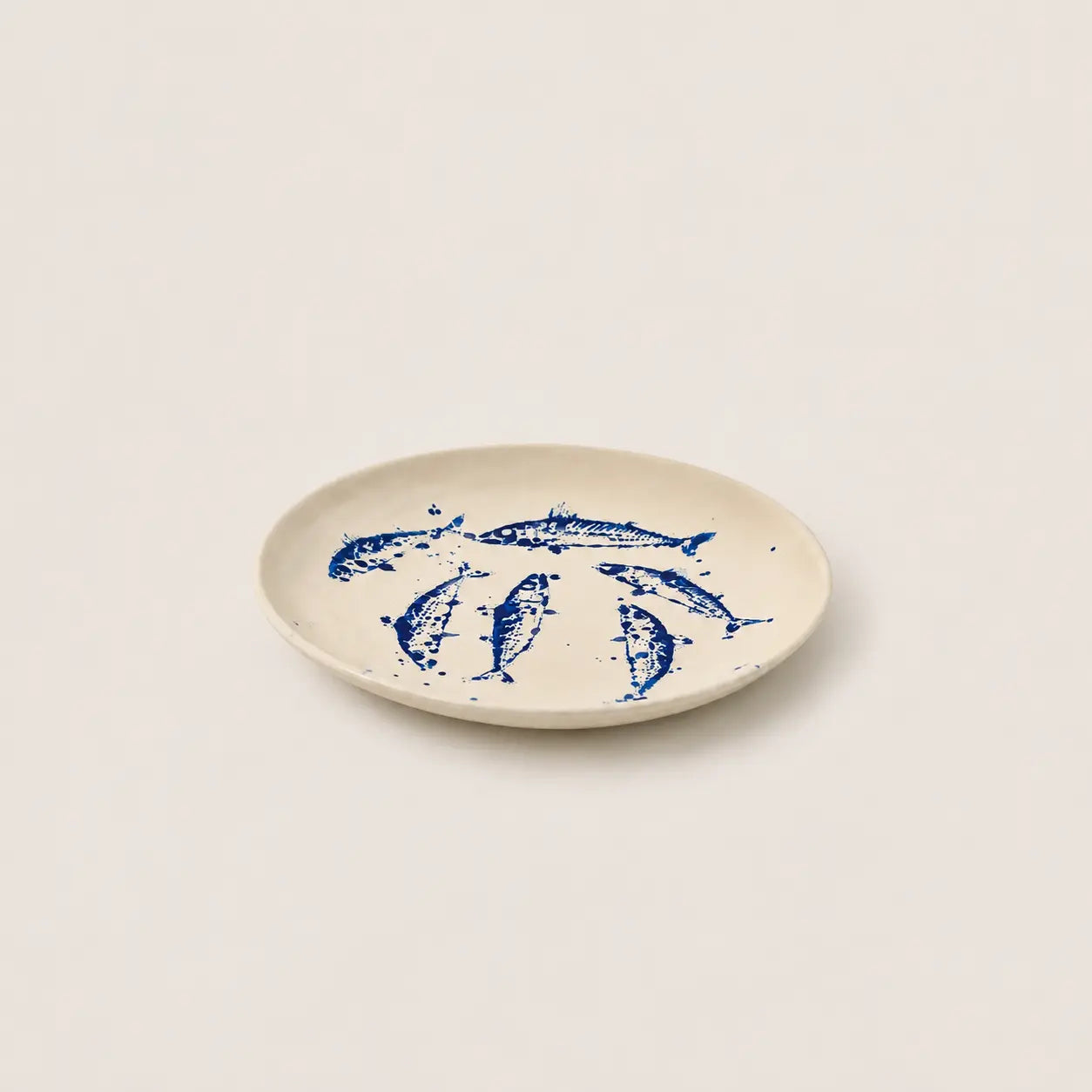 Beige plate with blue fish illustrations on a white background