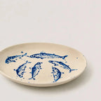 Beige plate with blue fish illustrations on a white background