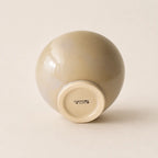 A glossy ceramic soup bowl with a rounded, dome-like shape, shown from its base. The bowl has a warm beige-gray glazed exterior and a cream-coloured unglazed base with the brand name 'CARDOON STUDIO' visible.