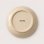 The underside of a round ceramic soup bowl in a warm cream-beige glaze, featuring the black printed brand name 'CARDON STUDIO' in the centre, set against a clean white background.