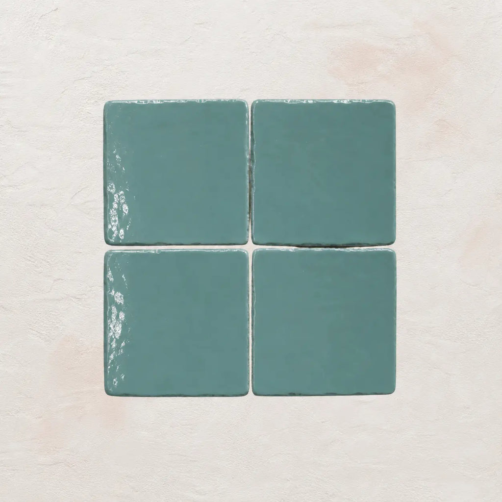 Four sky blue ceramic tiles on a textured beige surface