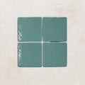 Four sky blue ceramic tiles on a textured beige surface
