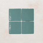 Four sky blue ceramic tiles on a textured beige surface