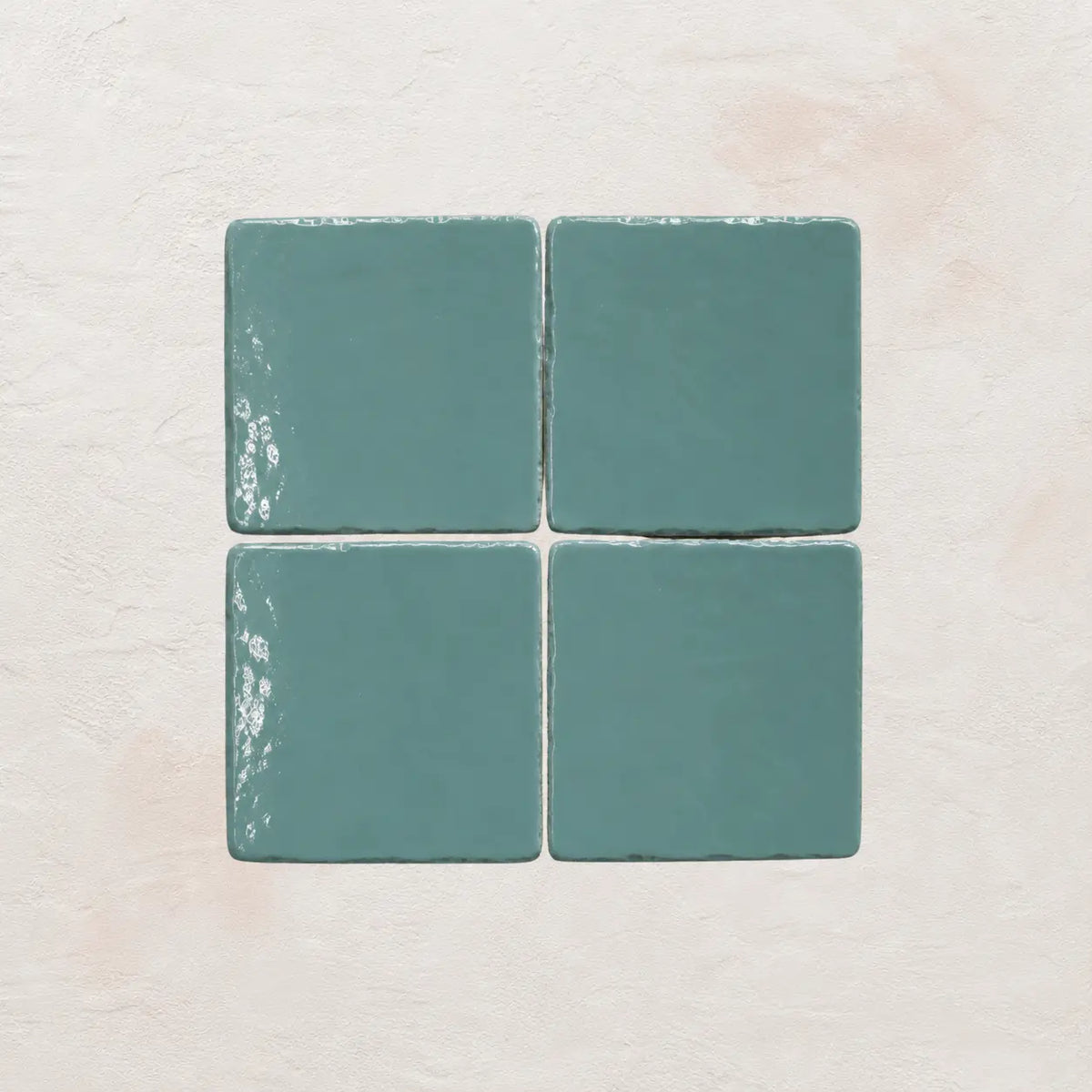 Four sky blue ceramic tiles on a textured beige surface