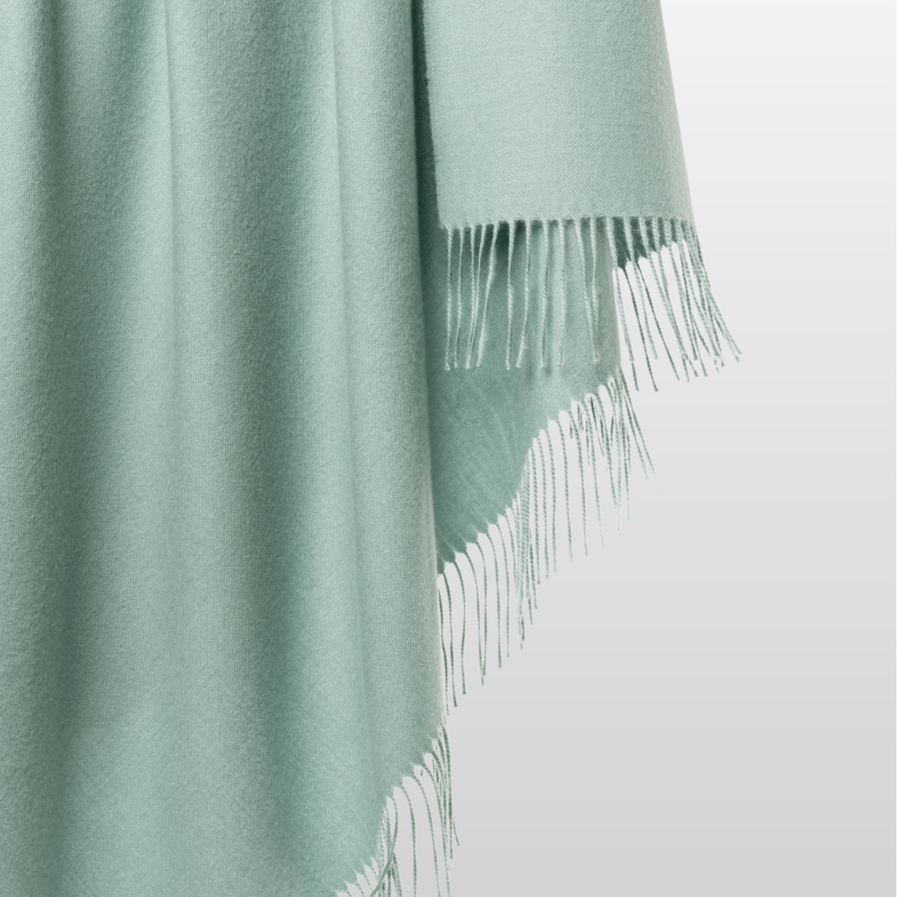 100% alpaca Solace Throw in Duck Egg Green colour. The woven textile drapes fluidly to showcase its airy texture, natural fibers, and minimalist design.
