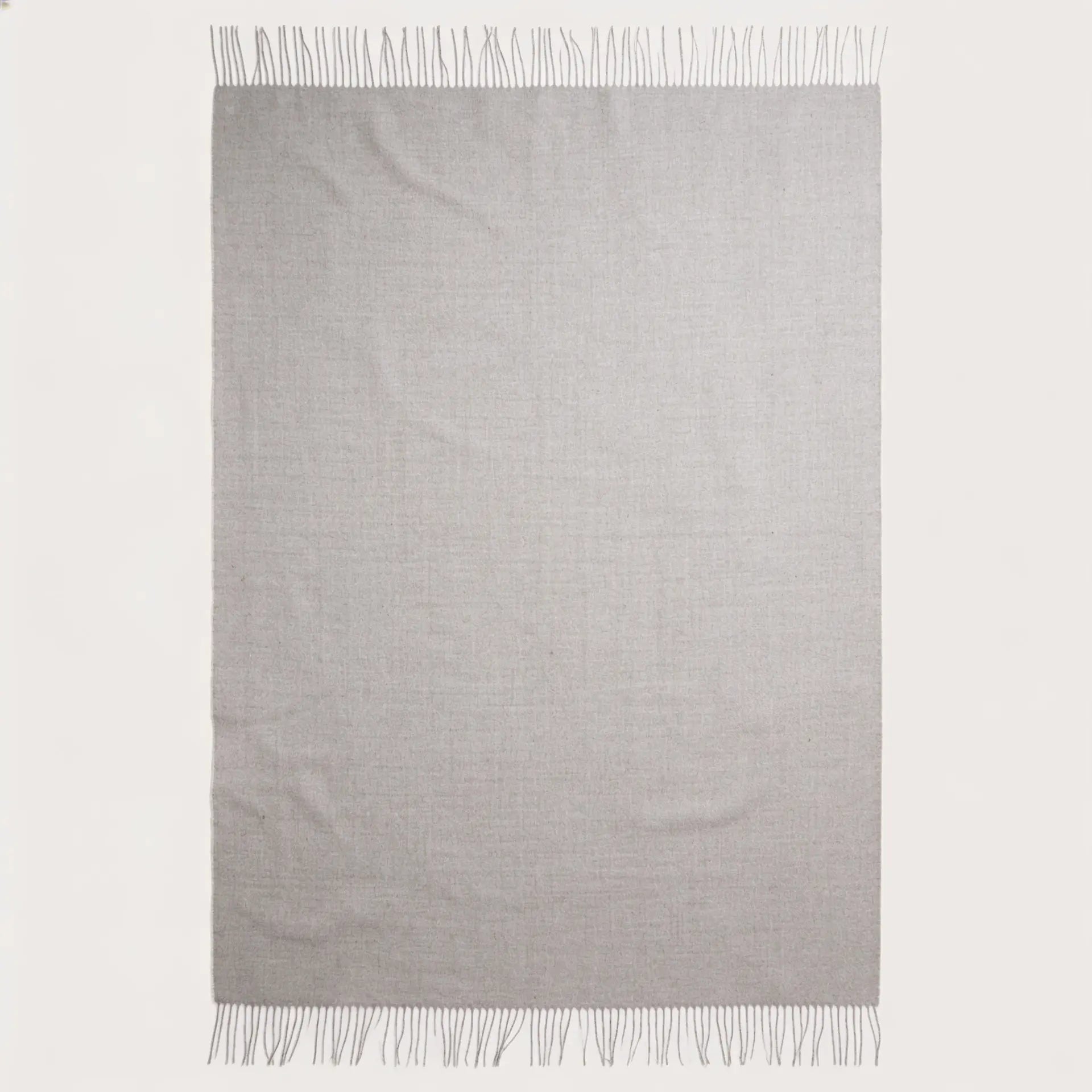 A light gray woven throw blanket with fringed edges, displayed flat against a solid off-white background.