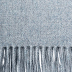 Close-up of a textured denim blue throw blanket with fringes at the bottom.