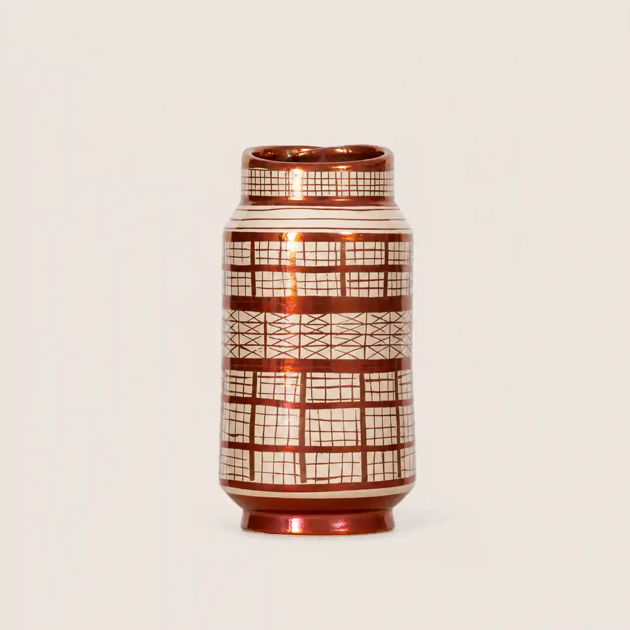 A small cylindrical ceramic vase with a glossy metallic copper-brown finish and a white grid pattern, set against a plain light beige background.