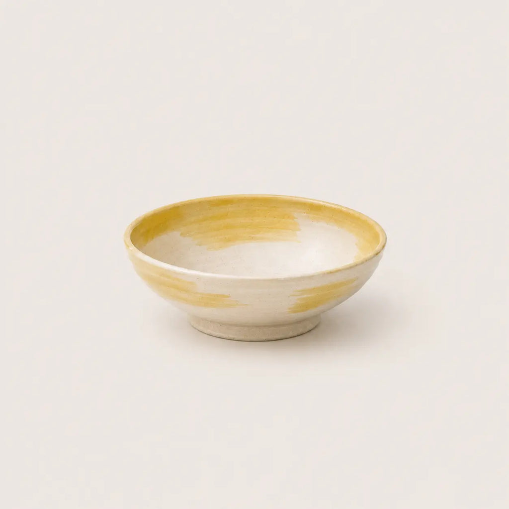 Ceramic snack bowl with yellow and white design on a light gray background