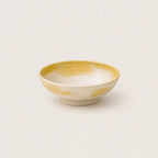 Ceramic snack bowl with yellow and white design on a light gray background