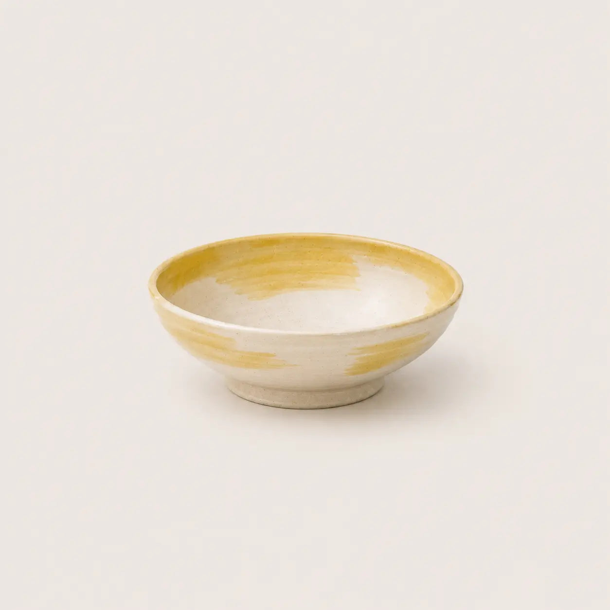Ceramic snack bowl with yellow and white design on a light gray background