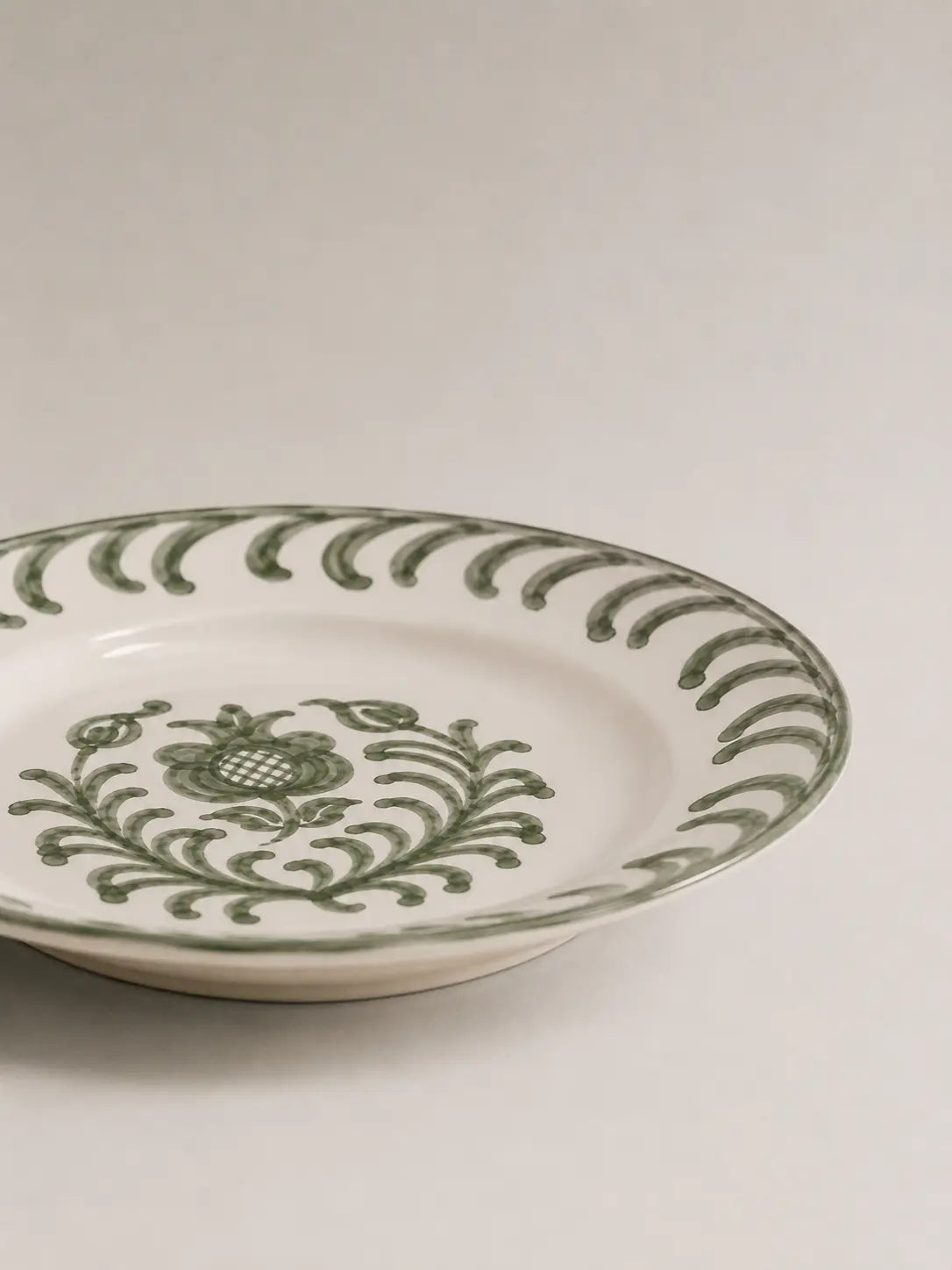 Ceramic plate with green floral pattern on a white background