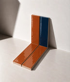 Glossy terracotta orange and marine blue handmade ceramic tiles arranged against a white wall in natural sunlight.